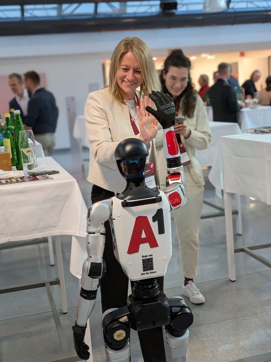 Besucherin gibt dem A1 gebrandeten Unitree G1 Event Robot beim A1 Business Forum 2026 ein High Five