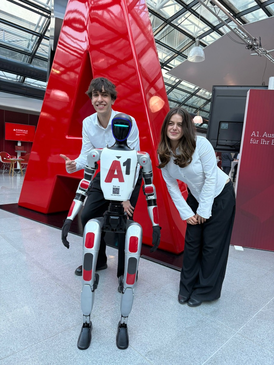 Unitree G1 Roboter mit zwei Besuchern vor dem roten A1 Markenlogo