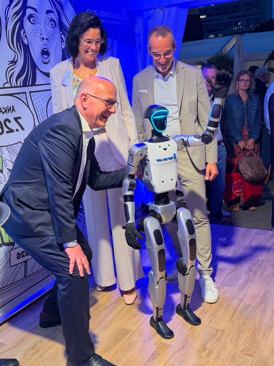 Drei Gäste erleben den Unitree G1 am Stand von STADT UND LAND beim Berliner Hoffest