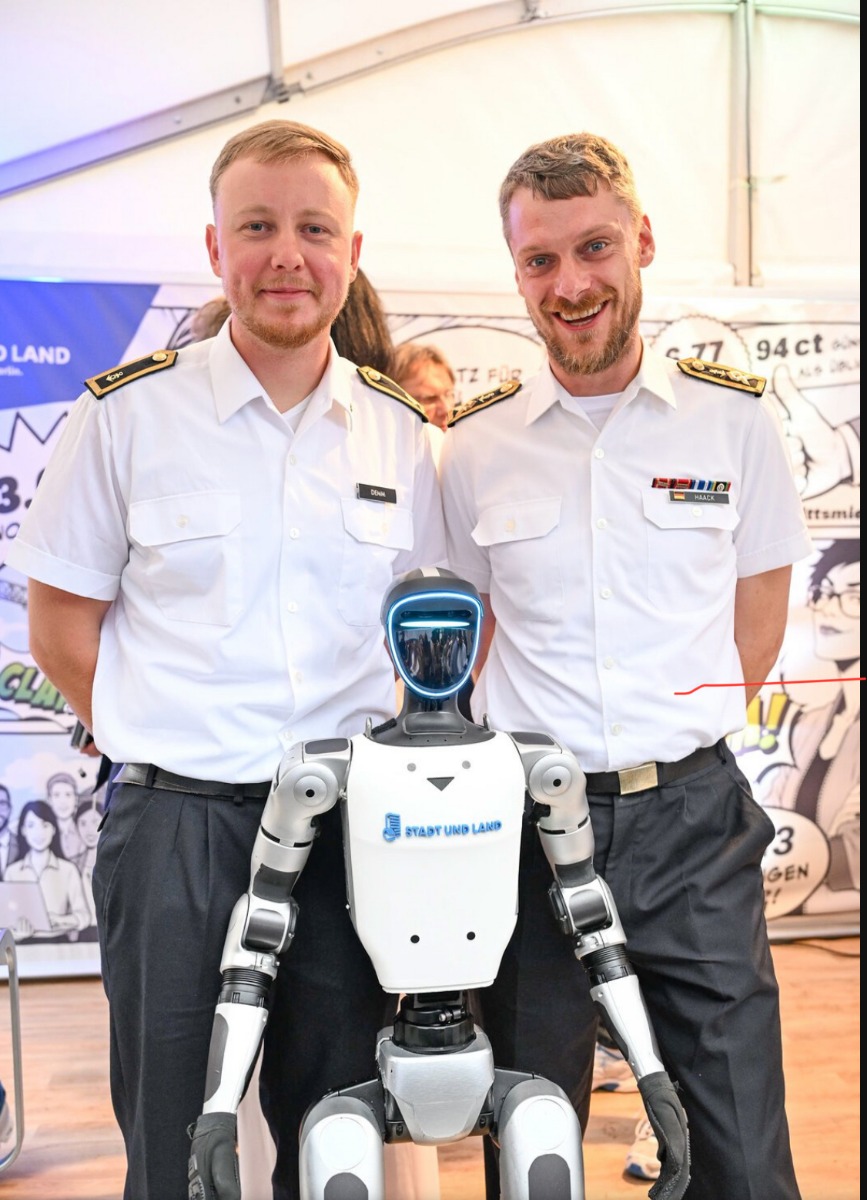 Zwei Gäste in Uniform posieren mit dem Unitree G1 beim Berliner Hoffest