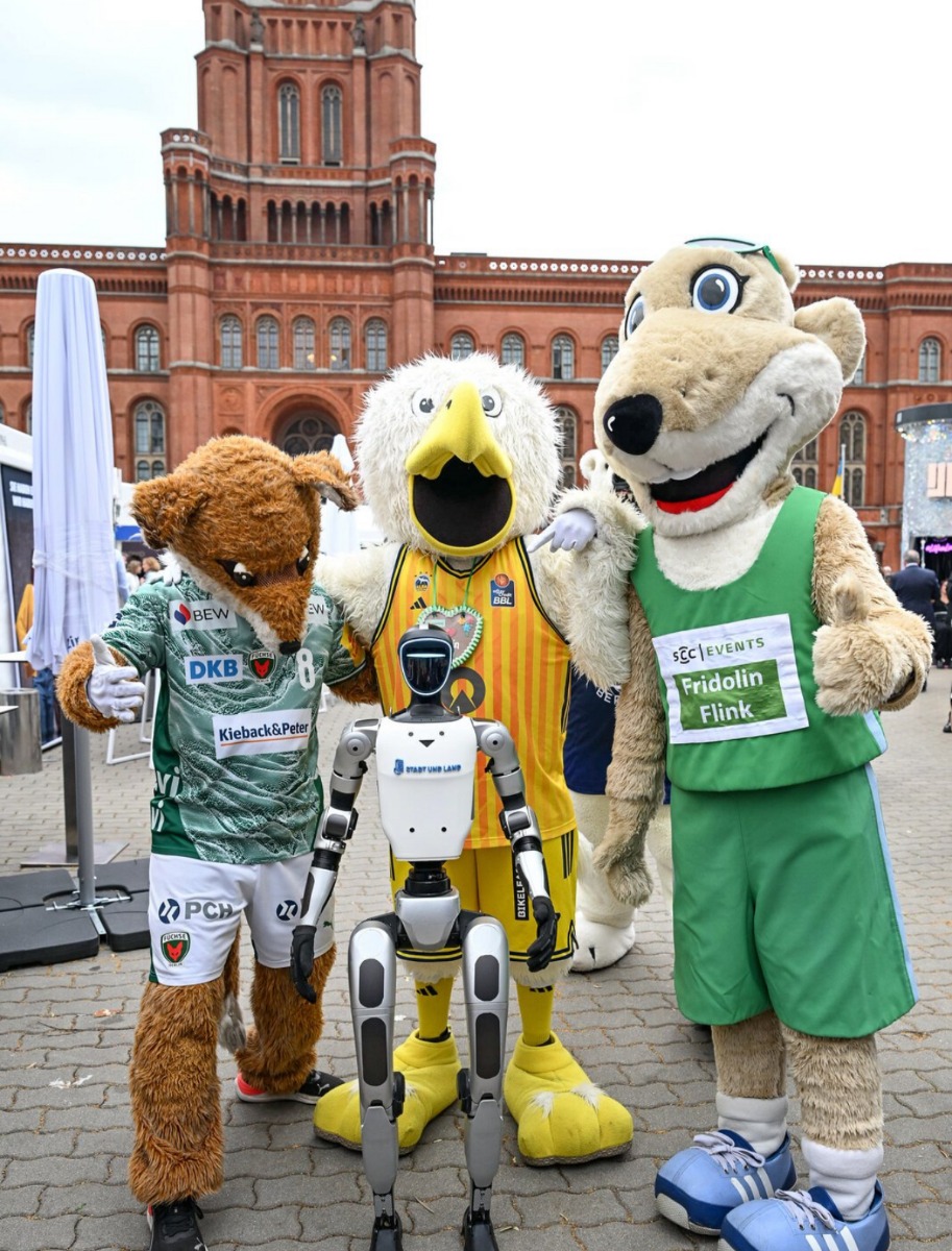 Drei Maskottchen und der Unitree G1 im Innenhof des Roten Rathauses