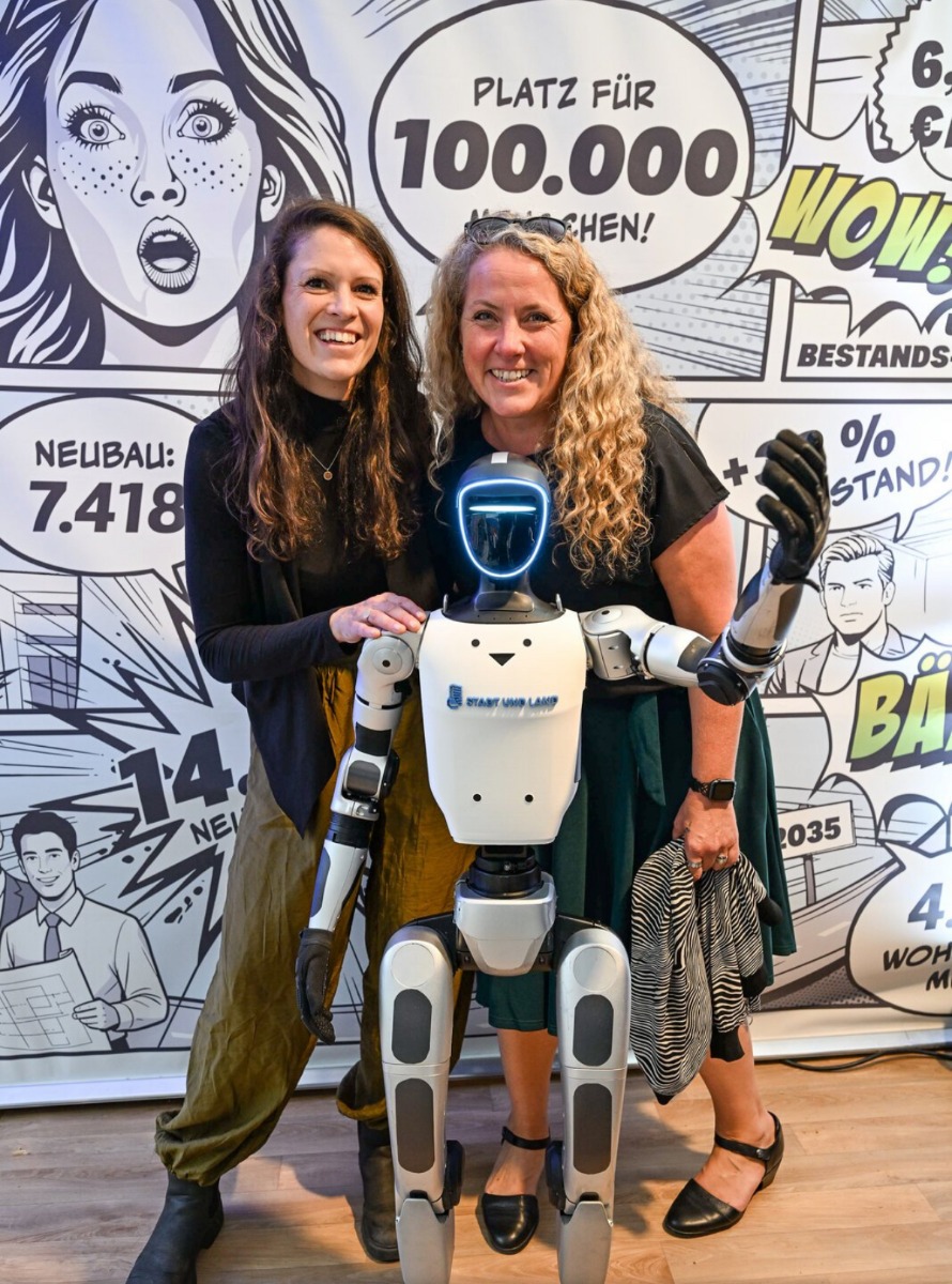 Zwei Besucherinnen mit dem Unitree G1 vor der STADT UND LAND Fotowand beim Berliner Hoffest 2026
