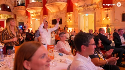 Gäste an den Galatischen jubeln und heben die Arme im beleuchteten Festsaal