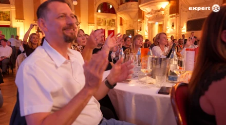 Gast im weißen Hemd applaudiert am festlich gedeckten Tisch der expert-Gala