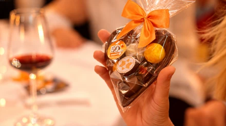 Schokoladenherz mit orangefarbener Schleife und expert-Jubiläumsdekoration