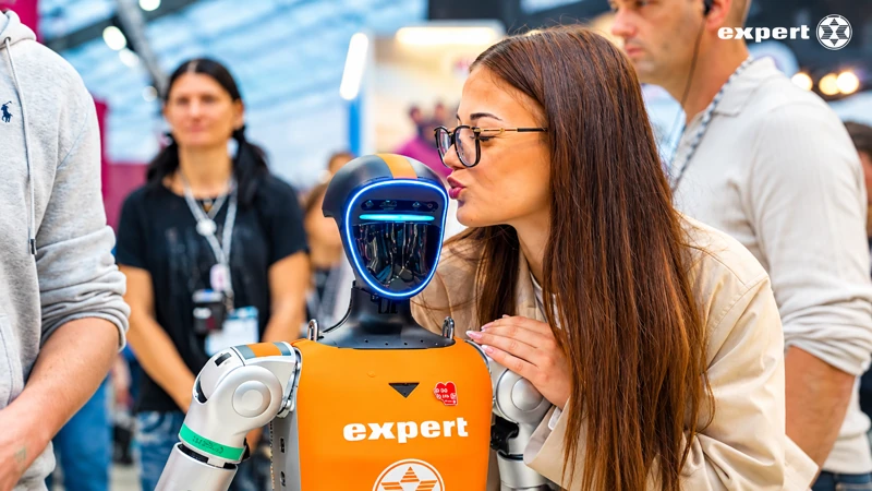 Besucherin mit Brille begegnet dem Unitree G1 aus nächster Nähe am expert-Messestand