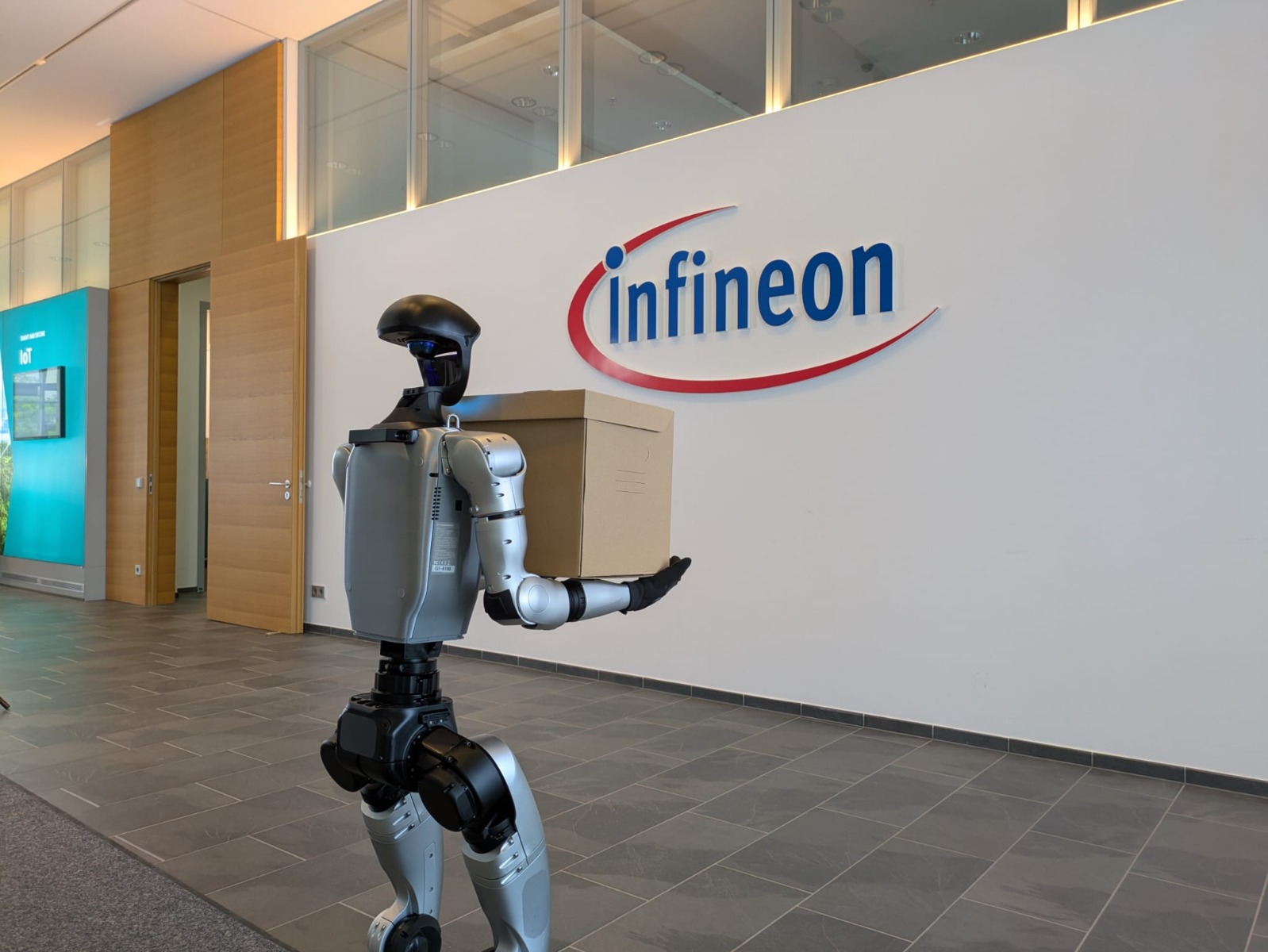 Unitree G1 vor der Infineon-Logo-Wand in Seitenansicht