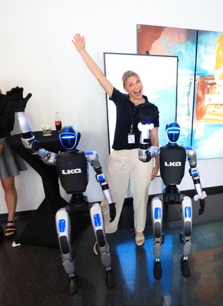 Besucherin winkt mit humanoiden Robotern beim LKQ Europe Premium Event 2026