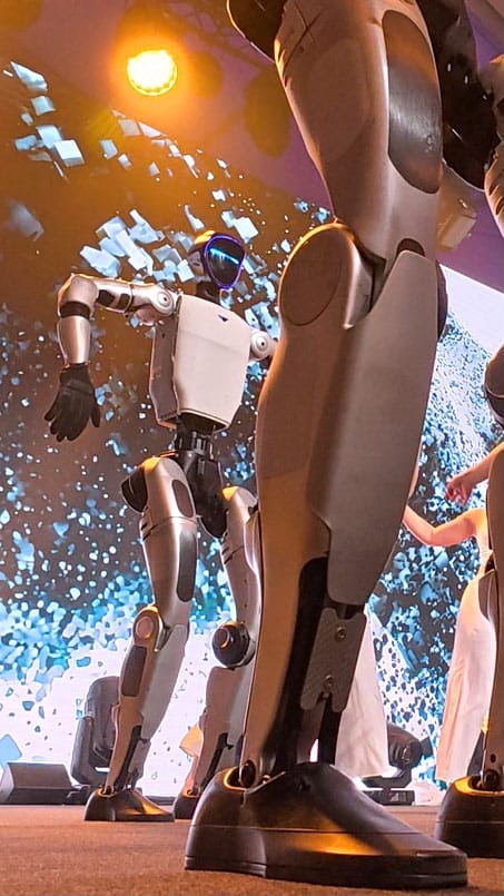 Unitree G1 Roboter und Tänzerinnen aus niedriger Perspektive auf der Bühne