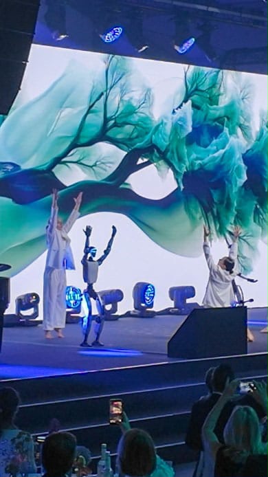 Unitree G1 Roboter und Tänzerinnen auf blau beleuchteter Bühne