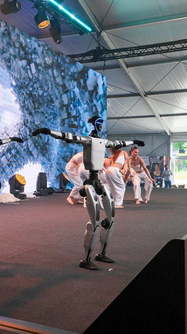 Unitree G1 Roboter und Tänzerinnen in seitlicher Bühnenansicht