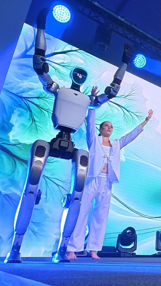 Unitree G1 Roboter und Tänzerin in blauer Bühnenbeleuchtung