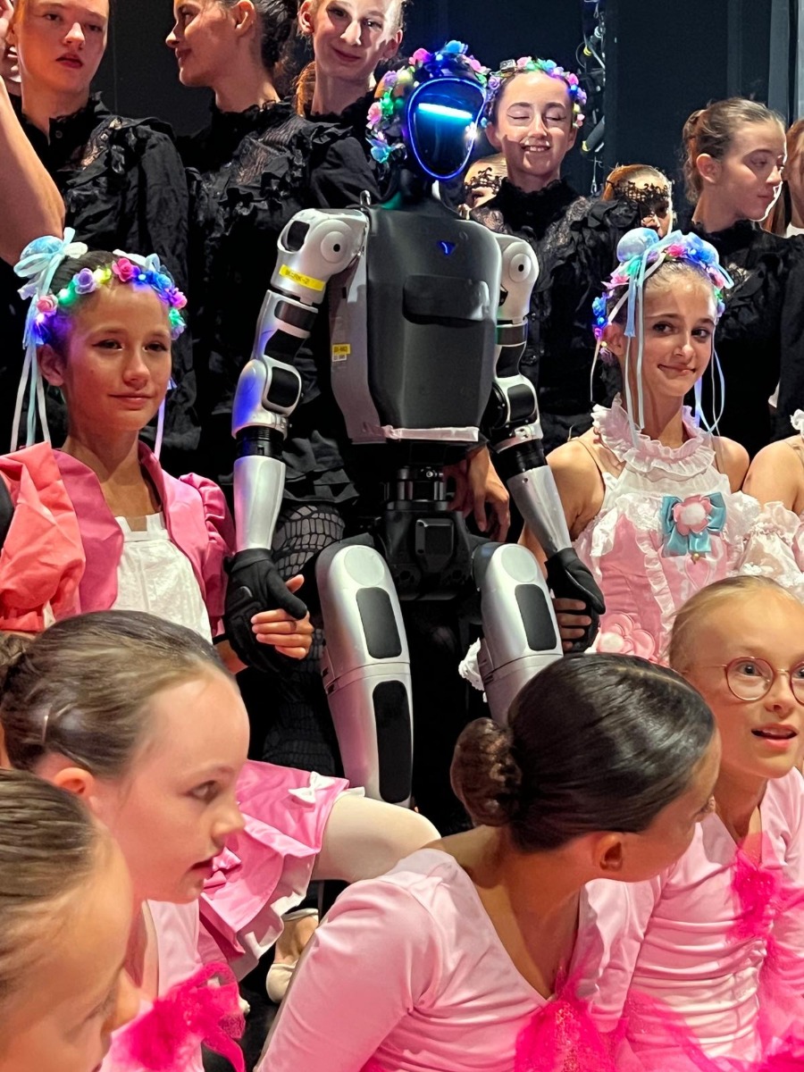 Nahaufnahme des Unitree G1 mit Tänzerinnen in pink-weißen Kostümen