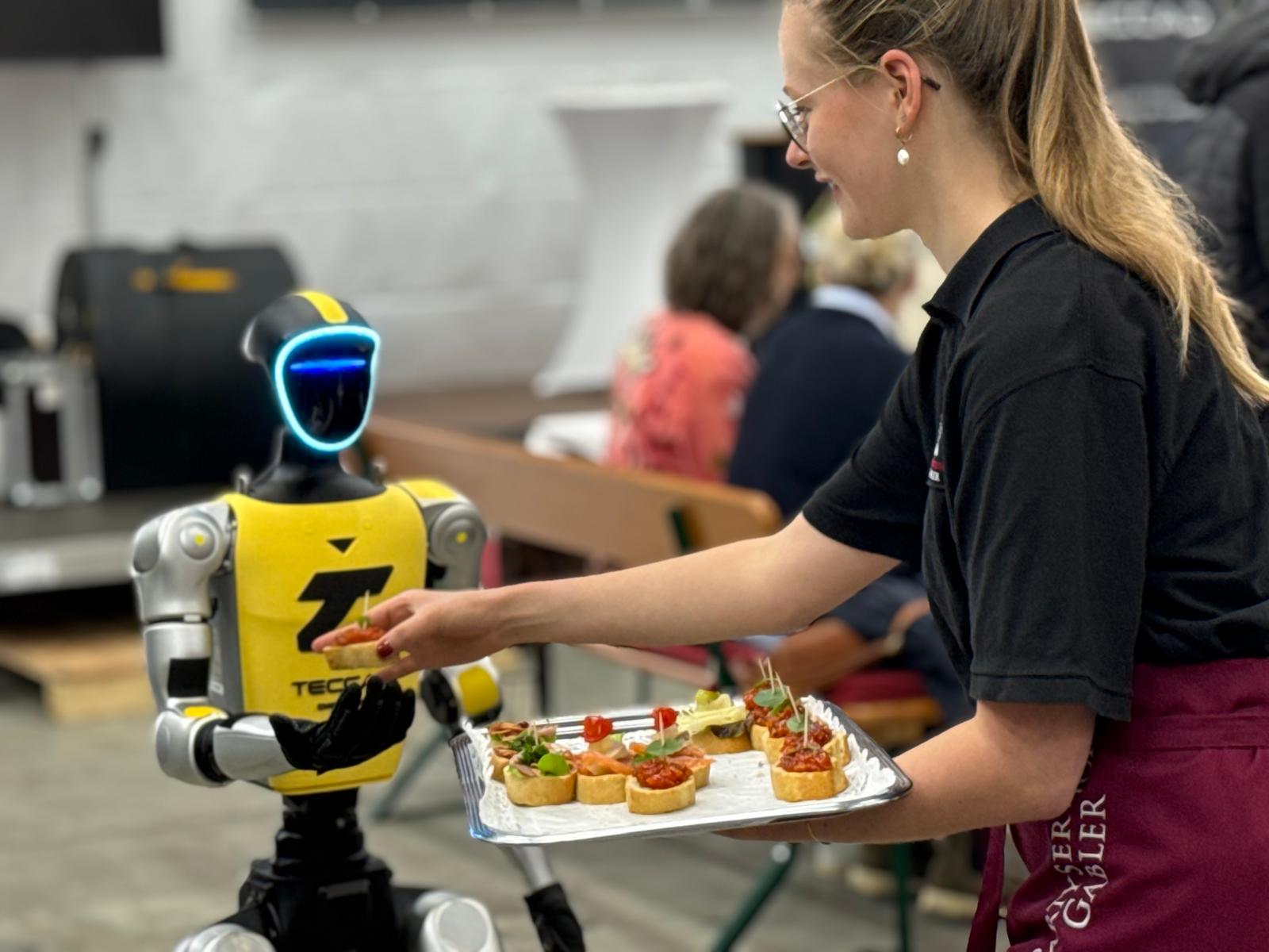 Humanoider Roboter Alfons interagiert mit Gästen im Cateringbereich des TECCAD-Jubiläums