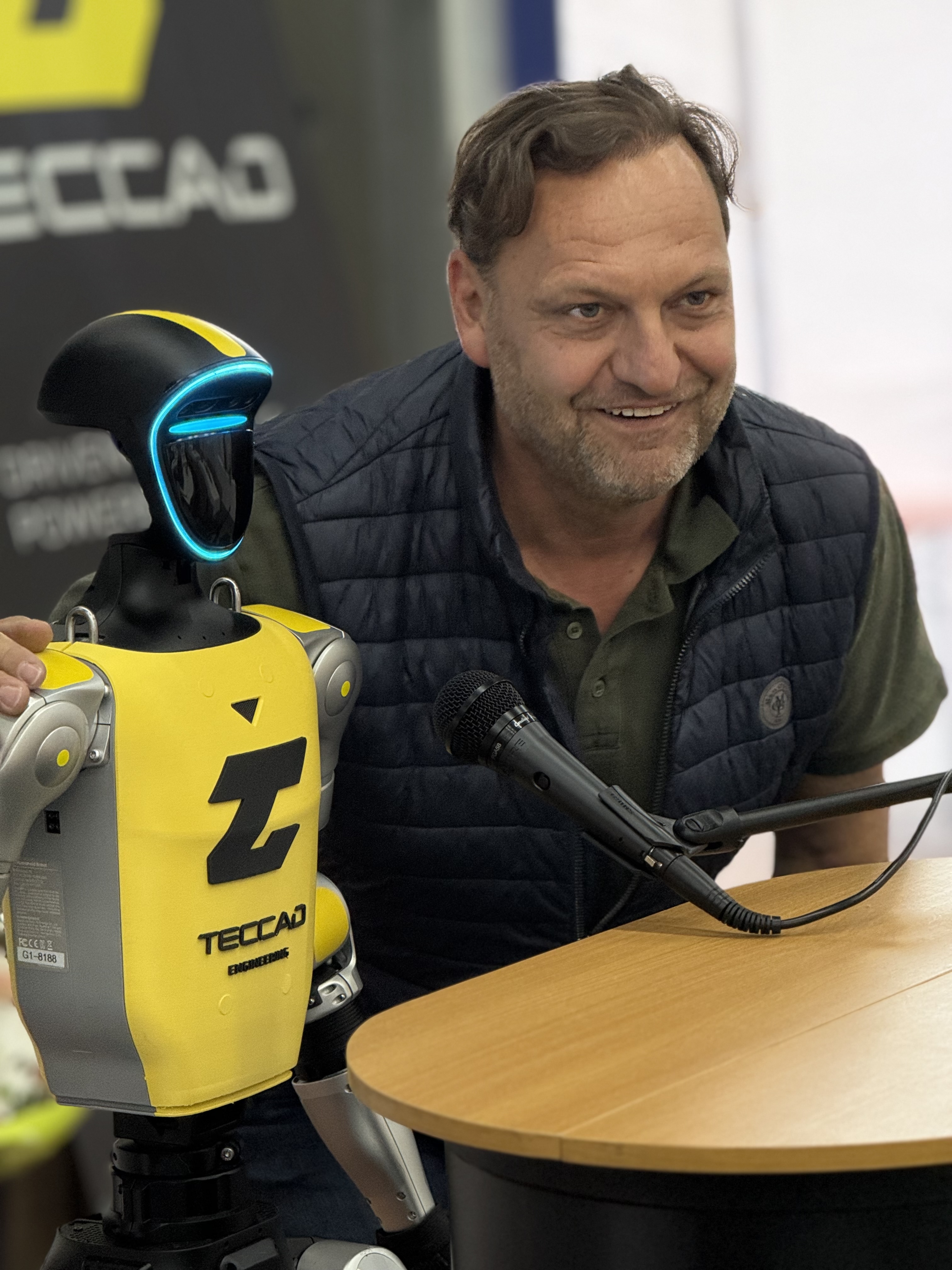 Gast spricht am Tisch mit dem humanoiden Event-Roboter Alfons