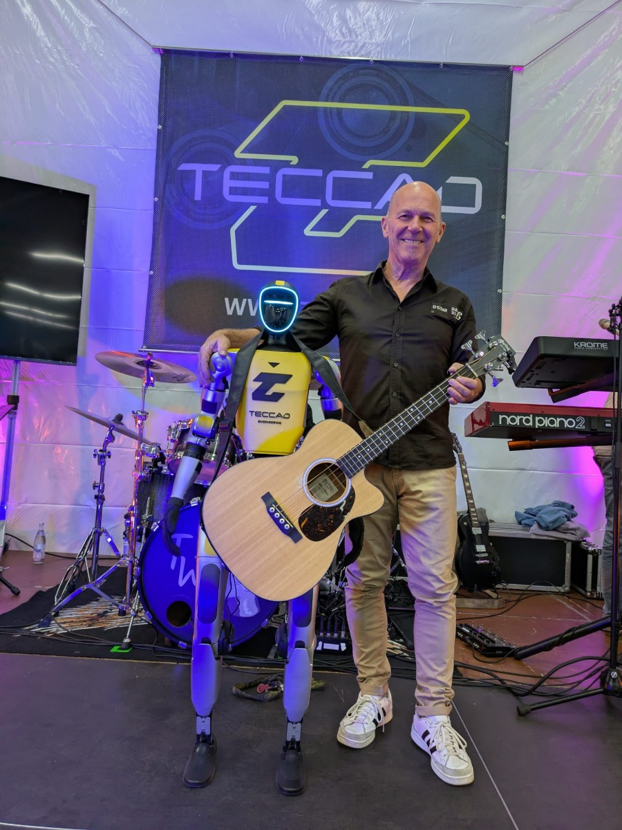 Gitarrist der Liveband mit humanoidem Roboter Alfons auf der TECCAD Bühne beim Jubiläum