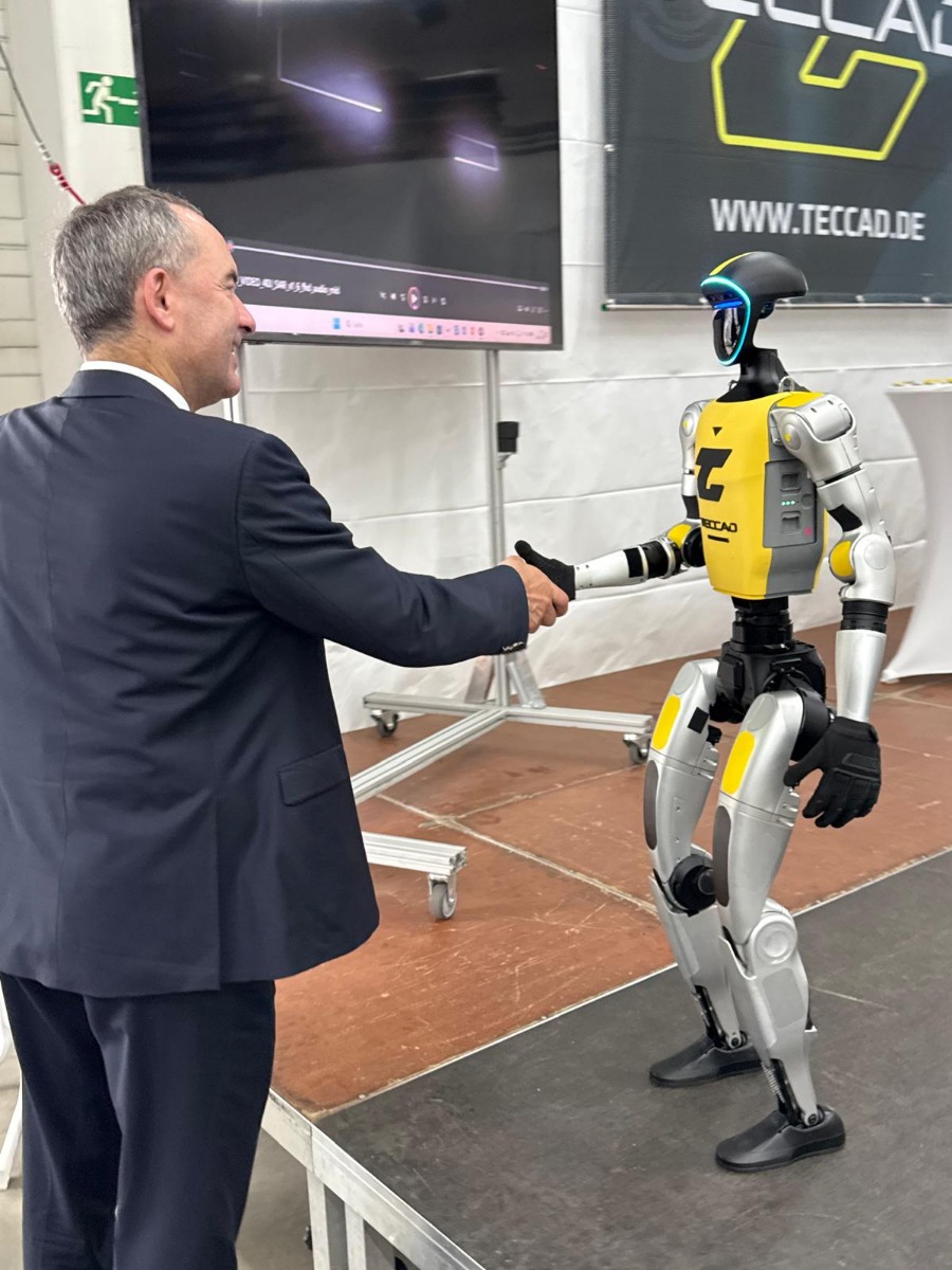 Hubert Aiwanger begrüßt den humanoiden Roboter Alfons auf der Bühne beim 20-jährigen TECCAD-Jubiläum