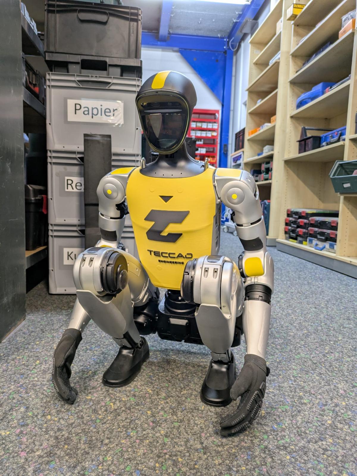 Humanoider Roboter Alfons vor Industrieregalen im TECCAD-Eventsetup