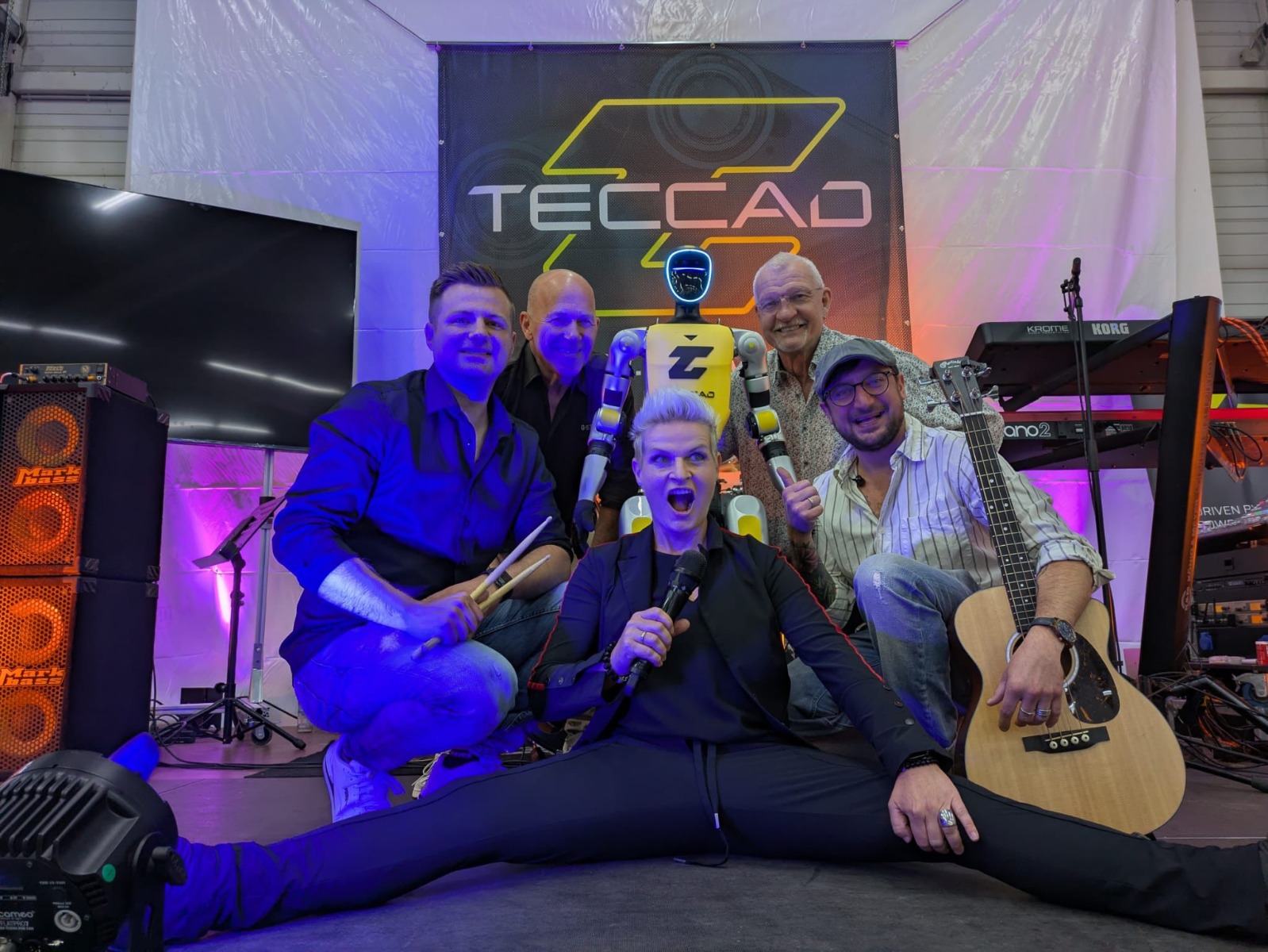 Liveband Gruppenfoto mit humanoidem Roboter Alfons auf der Bühne beim 20-jährigen TECCAD Jubiläum